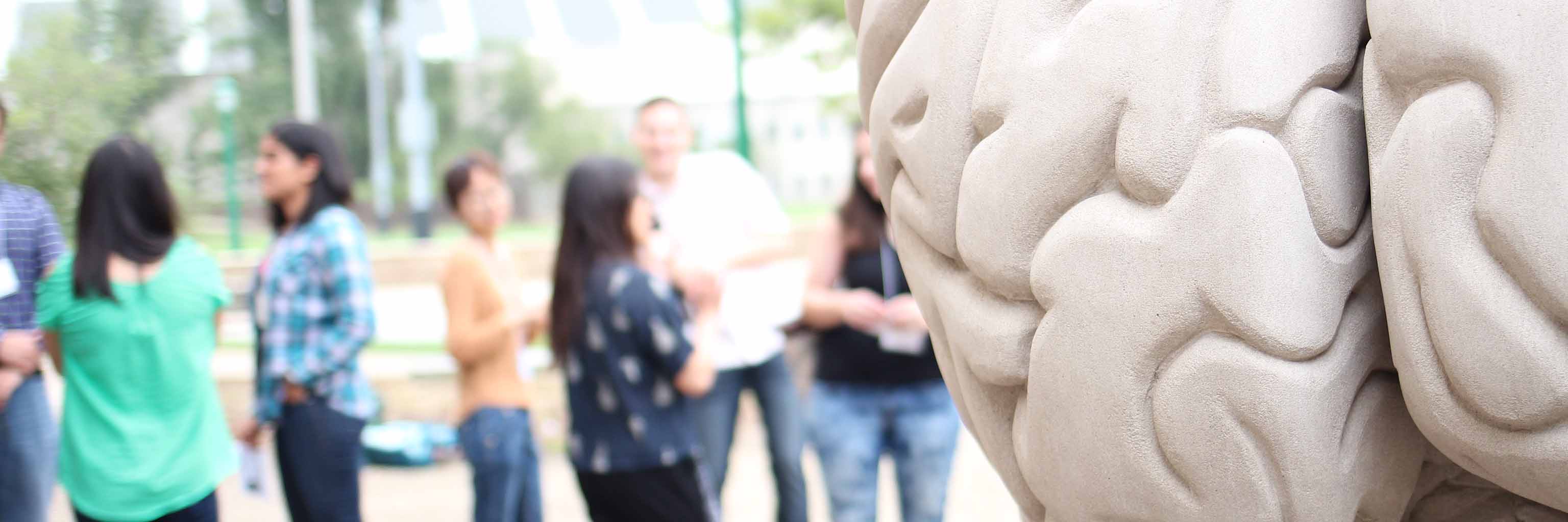 student in a group standing next to human brain statue
