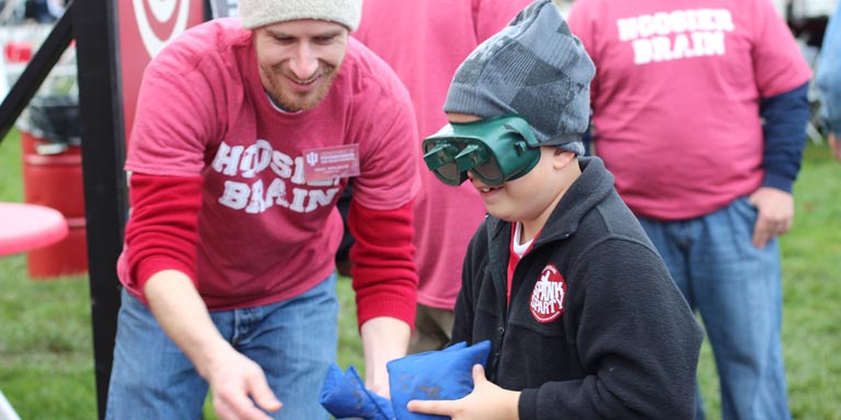 student and child wearing goggles interacting outside