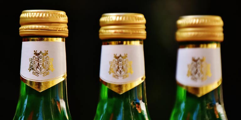 three green bottles of beer with gold caps